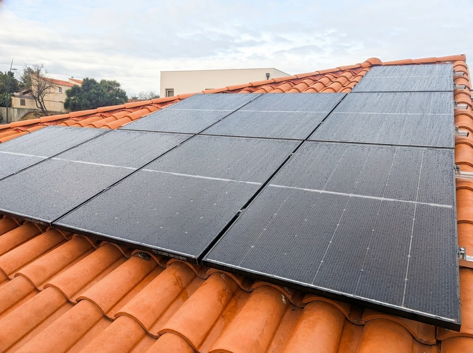 Toiture en tuiles canal orangées avec installation de panneaux solaires photovoltaïques monocristallins noirs