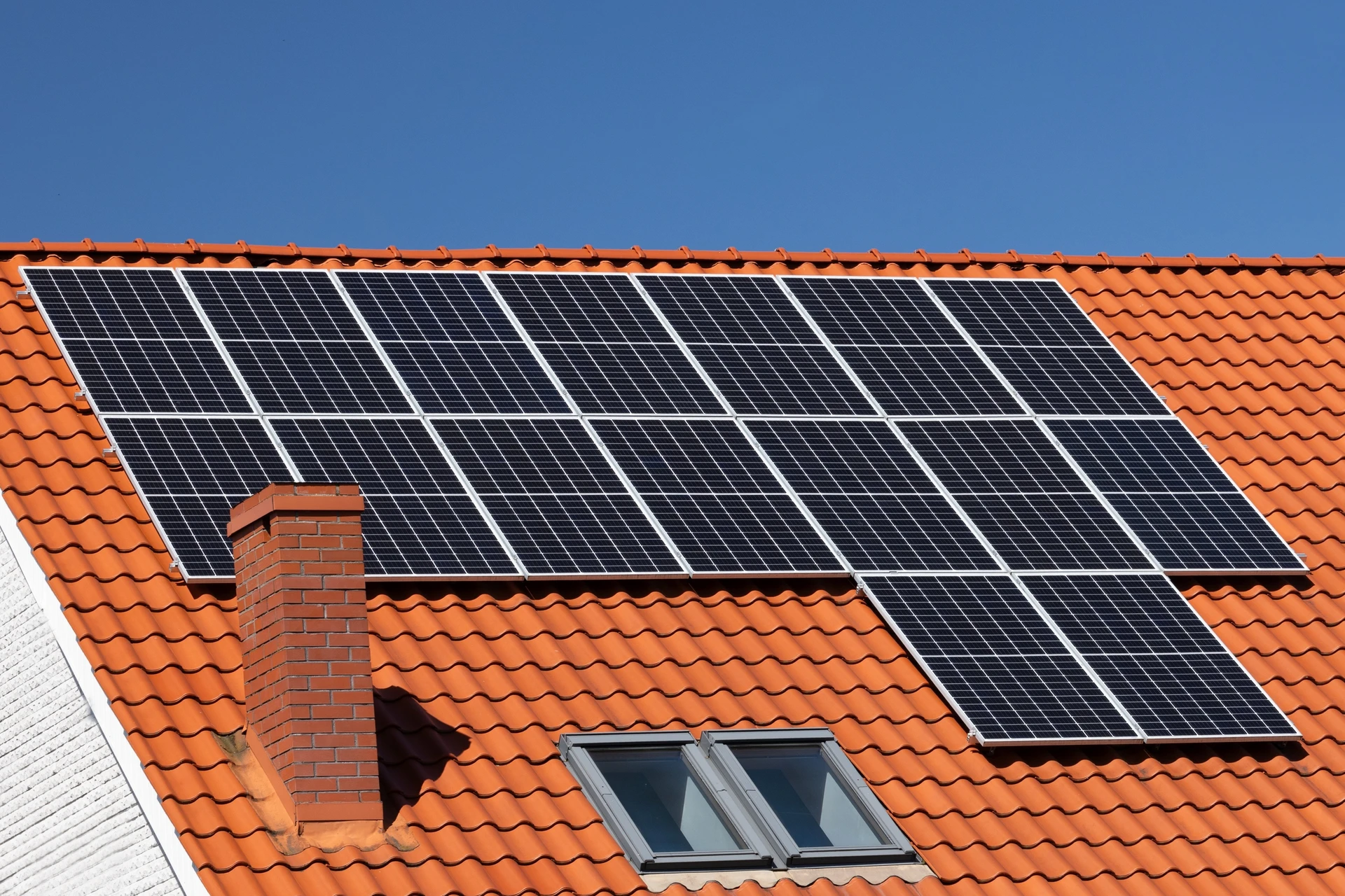 Toiture résidentielle avec installation de panneaux solaires photovoltaïques sur tuiles en terre cuite orange
