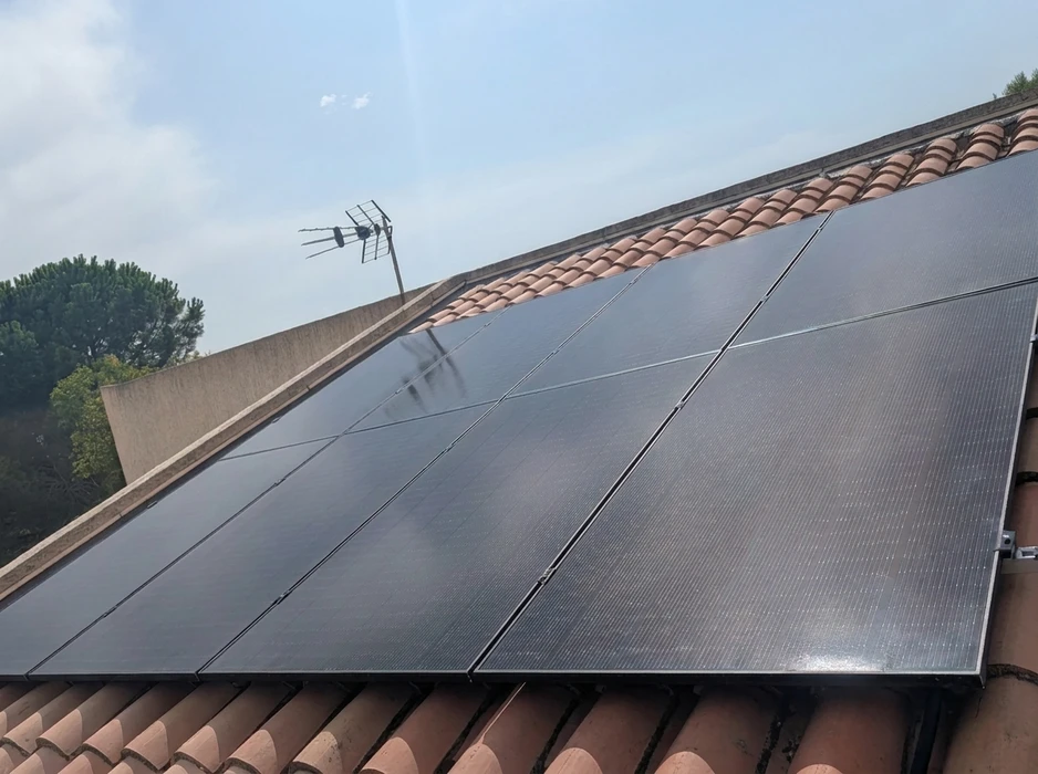 Toiture en tuiles canal terre cuite avec installation de panneaux solaires photovoltaïques monocristallins noirs, montés sur rails d'aluminium