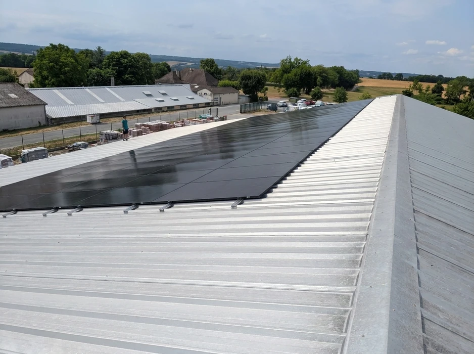 Toiture résidentielle équipée de panneaux solaires photovoltaïques sous un ciel bleu nuageux